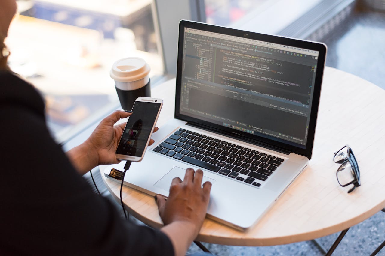 Crafting Captivating Headlines: Your awesome post title goes here Developer working remotely, coding on a laptop with phone in hand, showcasing modern work culture.