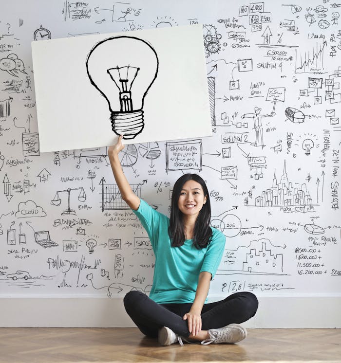 Mastering the First Impression: Your intriguing post title goes here Young woman holds a light bulb drawing against a creative brainstorming wall.