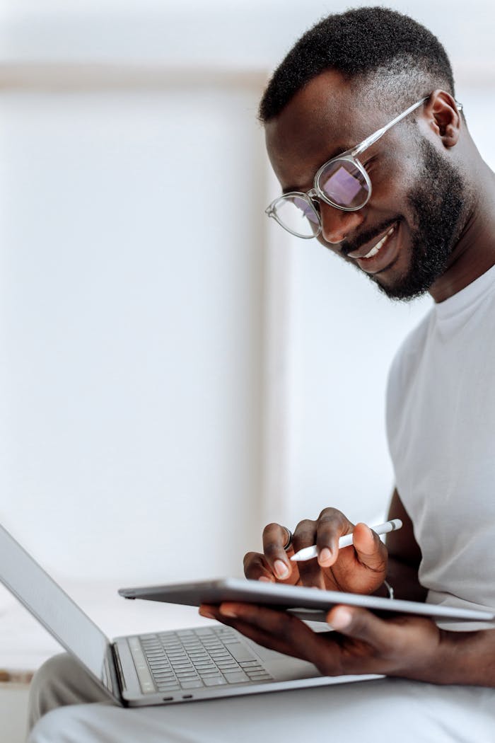 The Art of Drawing Readers In: Your attractive post title goes here A smiling man using a tablet and laptop in a bright indoor setting. Perfect for technology and lifestyle themes.